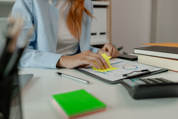 a businesswoman is working in her office and writing a note, a female employee is writing a brief...