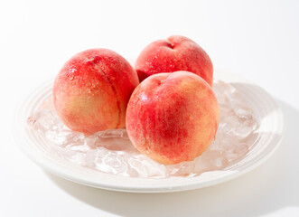 Cut peaches and ice on a plate on white background.