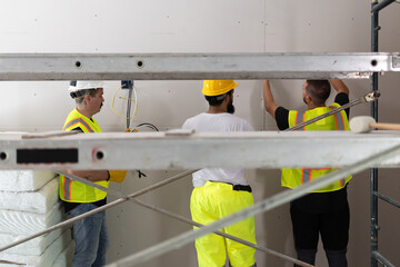 On a house remodeling site, a committed team, including a man in a helmet and bright vest,...