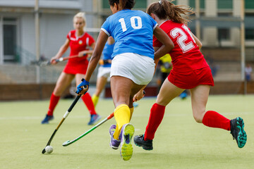 Female players compete for the ball during an attack in a field hockey match