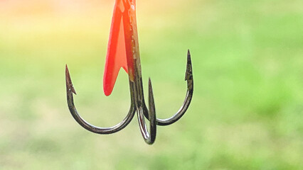 A hook with a red and silver piece of bait on it. The hook is hanging from a fishing line