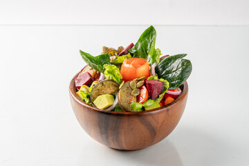A fresh and colorful salad with assorted vegetables in a wooden bowl, perfect for a healthy meal or vegan diet.