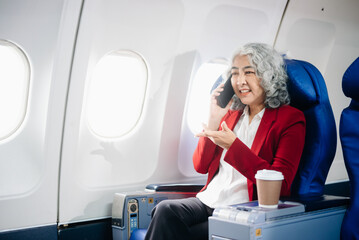  Asian seniorexecutive excels in first class, multitasking with digital tablet, laptop and...
