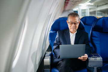 Asian senior executive excels in first class, multitasking with digital tablet, laptop and smartphone. Travel in style, work