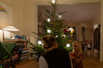 Mother and daughter decorating Christmas tree at home