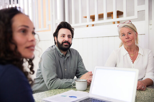 Business colleagues sitting at desk looking away in office during meeting