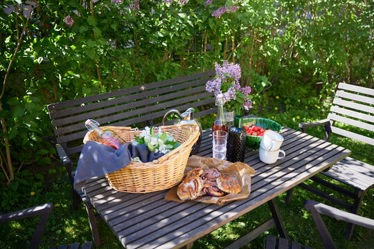 High angle view of fresh snacks and basket with drinks on table near plants at back yard