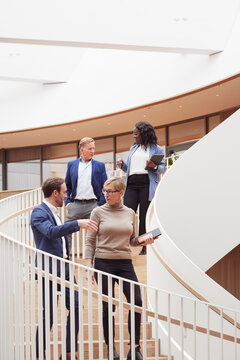 Low angle view of corporate colleagues talking while moving down on steps