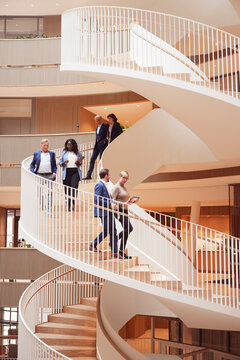 Low angle view of multiracial colleagues talking while moving down on steps in office