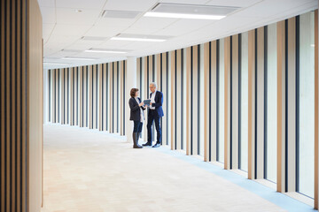 Businessman and businesswoman discussing over digital tablet in office lobby