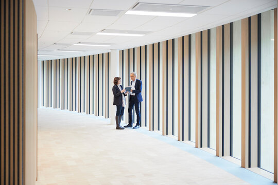 Businessman and businesswoman discussing over digital tablet in office lobby