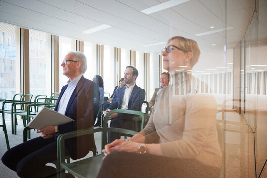Corporate colleagues attending seminar in office seen through glass