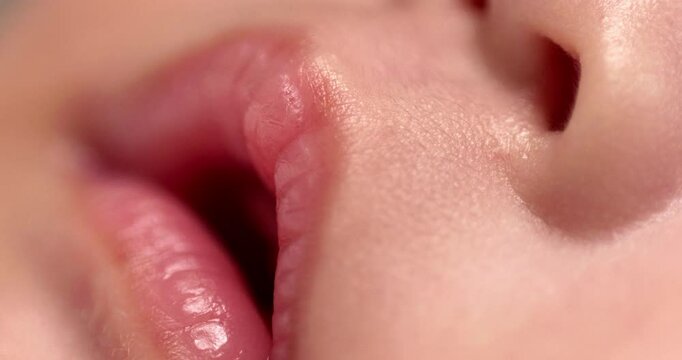 Close-up shot of a newborn baby's open pinkish lips and its nostrils, as it is sleeping soundly.