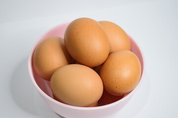 Close up view of chicken eggs in the pink bowl isolated on white background