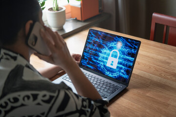 Woman talking on phone with encrypted laptop on table at home