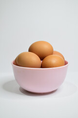 Side view of chicken eggs in the pink bowl isolated on white background. Free space, copy space, empty space on the top. Potrait photo.