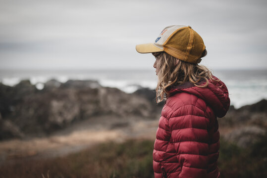 Side view of girl wearing padded jacket and cap at beach