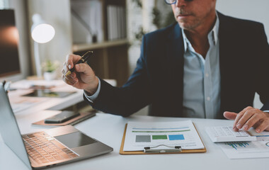 A skilled businessman sits at a desk and uses a computer to analyze online business marketing data....