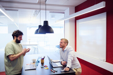 Smiling businessman making list during discussion with project manager