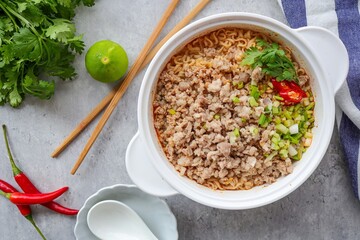Home made Noodle with minced pork,Tom yum with noodles ,  instant spicy noodles  , noodles tom yum with minced pork in white bowl on grey cement background