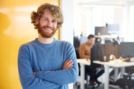 Portrait of confident young businessman with arms crossed against yellow cabinet