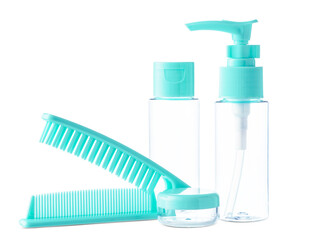 Clear cosmetic containers with turquoise lids and a comb arranged together on a white background