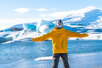 A person in a yellow jacket stands on a frozen lake, looking out at the water © unai