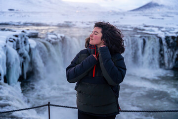 Portrait of a woman at the beautiful Godafoss waterfall in winter in Iceland