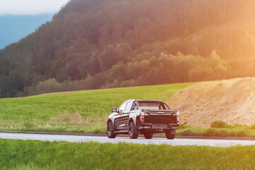 Black pickup truck driving through a scenic rural area © AlexGo