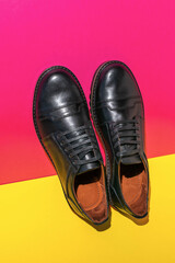 Elegant Black Leather Shoes on Vibrant Pink and Yellow Background - Stylish Men's Footwear Photography