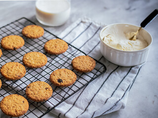 Freshly baked oatmeal cookies cooling on a black wire rack, with a light background and soft natural lighting. The cookies are golden brown with hints of raisins and a crispy texture, creating a cozy