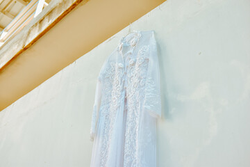 Wedding dress hanging on white wall