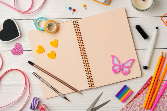 Creative workspace with colorful stationery and decorations on a white wooden desk