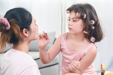 Mother teaches the child to do makeup. Mother and little daughter are doing makeup on each other and having fun.