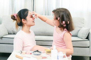 Young Asia mother and little daughter are doing make up for each other and having fun. Family spend time together have a fun in living room with happy holiday concept,happy family.
