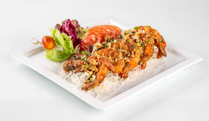 Delicious crispy fried shrimp served with fresh salad and garnished with chopped vegetables on a white plate.