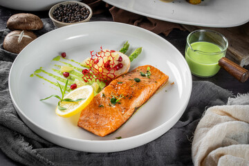 Delicious gourmet plate with grilled salmon, asparagus, garnished vegetables, and a lemon wedge on a rustic table setting.