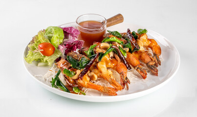 Delicious grilled shrimps with fresh salad and dipping sauce on a white plate, perfect for a healthy meal.