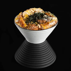 Delicious Japanese rice bowl with crispy fried chicken, seaweed, and egg, served in a unique striped bowl. Perfect for authentic Asian cuisine lovers.