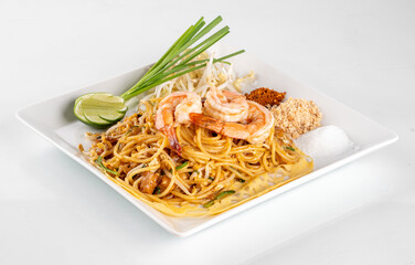 Delicious Pad Thai noodles with shrimp, lime, sprouts, and gourmet garnish on a white plate, ready...
