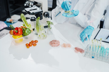 Two female researchers in the lab work at a desk on plant genetic modification for food, meat, and vegetables, utilizing advanced genetic engineering technology to enhance crops and animal feed.
