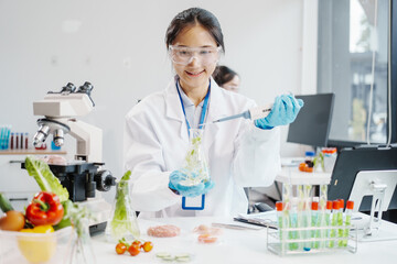 Two female researchers in the lab work at a desk on plant genetic modification for food, meat, and vegetables, utilizing advanced genetic engineering technology to enhance crops and animal feed.