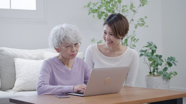 高齢者の母親にパソコンを教える娘（家族・ファミリー）
