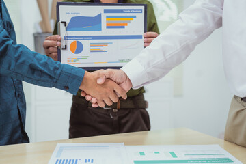 Close-up of business people shaking hands during a meeting in the office. The discussion revolves...