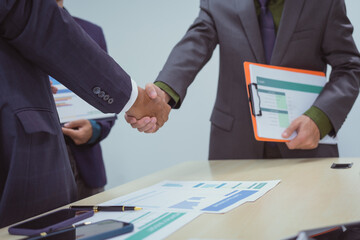 Close-up of business people shaking hands during a meeting in the office, discussing and analyzing charts,financial data,planning digital marketing projects together with business experts investors