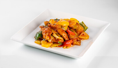 Delicious stir-fried chicken with colorful bell peppers, onions, and flavorful sauce served on a square white plate.