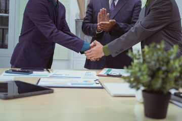 Close-up of business people shaking hands during a meeting in the office, discussing and analyzing charts,financial data,planning digital marketing projects together with business experts investors