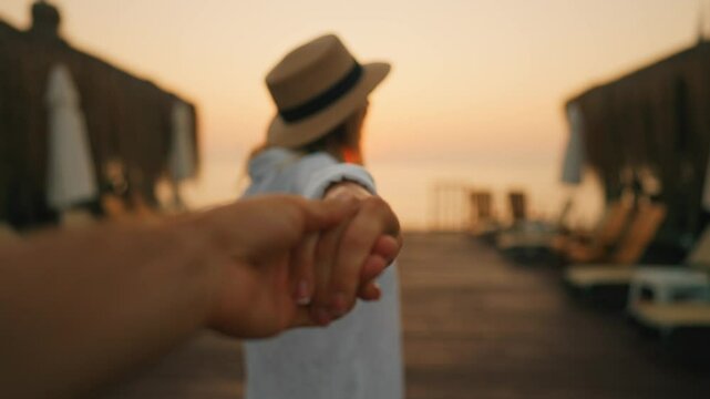 Follow me to sea, woman holding male hand and walking on pier, slow motion. Amazing seascape in sunset or sunrise, travelers admiring beautiful nature, trip to sea or ocean in vacation or holidays