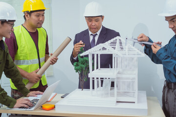 A male engineer and  contractor at a desk in an office discuss the structural design of a house,roof drafting, lot size and number of occupants for a dream home project,focusing on budget and style