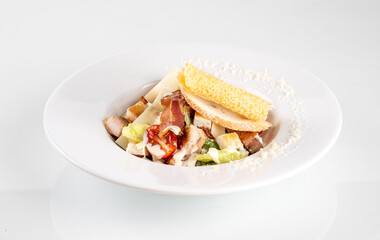 Elegant close-up of a classic Caesar salad served in a white bowl with croutons, bacon, and grated cheese on a white background.